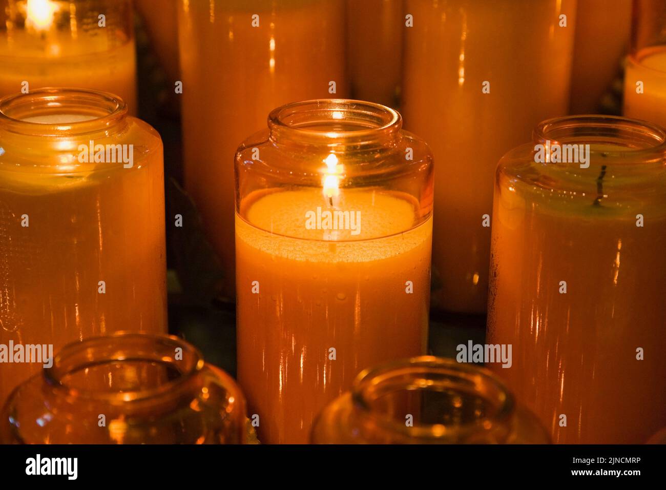 Orangefarbene Votivkerzen in der Kirche. Stockfoto