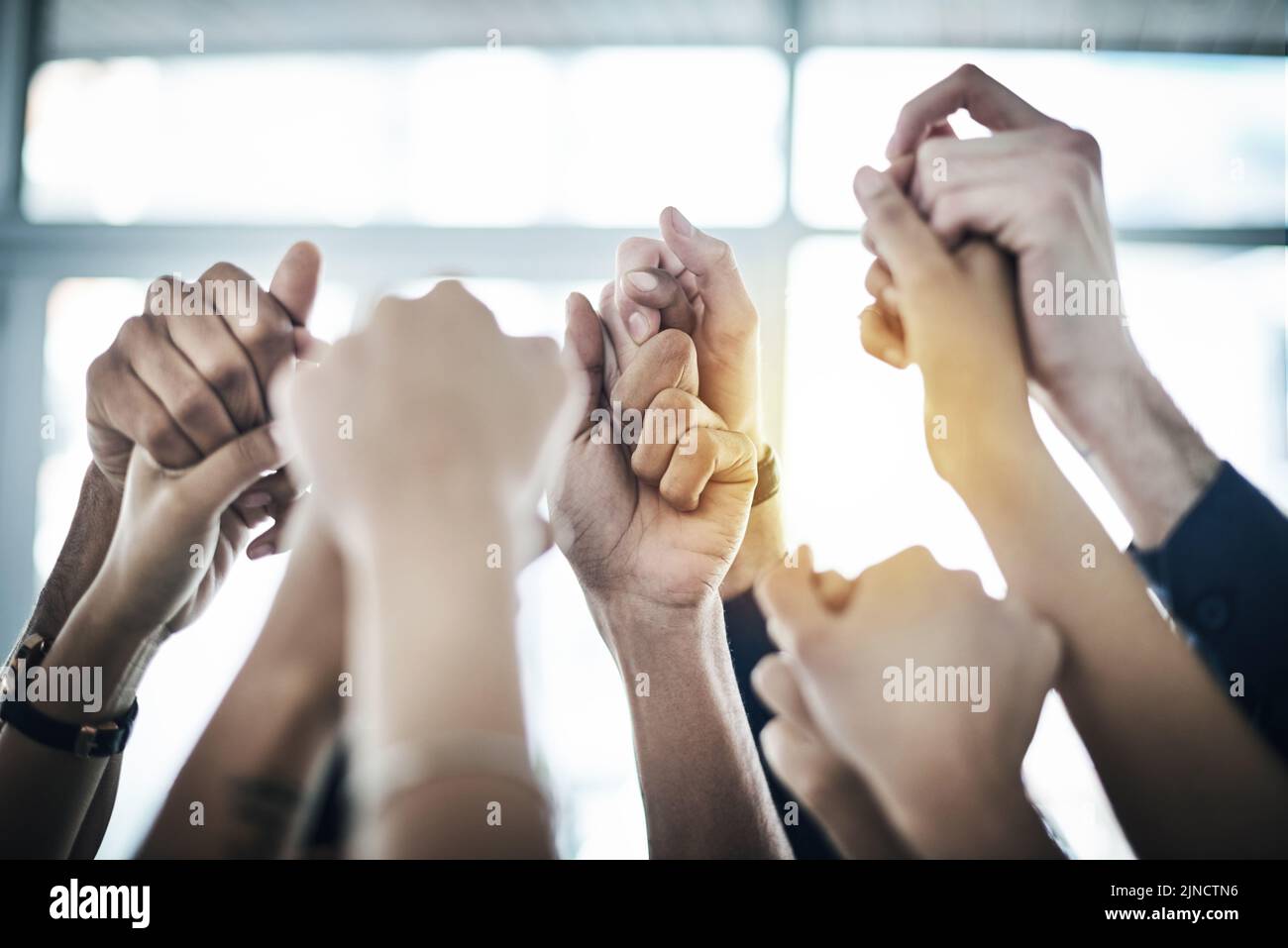 Wir haben uns gegenseitig den Rücken. Eine Gruppe von nicht erkennbaren Geschäftsleuten hält die Hände in Einheit zusammen. Stockfoto