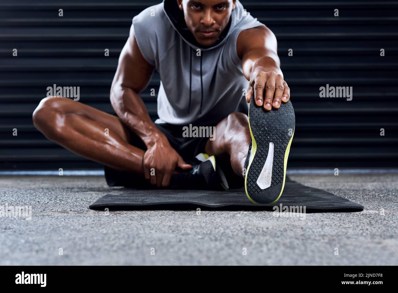 Übung, weil es gut für Sie. Ein sportlicher junger Mann, der seine Beine als Teil seiner Übung Routine streckt. Stockfoto