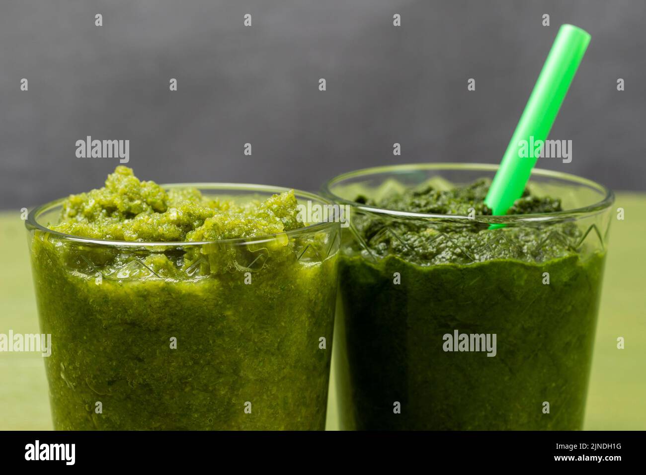 Zwei Gläser mit Gemüse-Smoothie. Grünes Stroh im Glas. Teil des Rahmens. Nahaufnahme. Speicherplatz kopieren Stockfoto