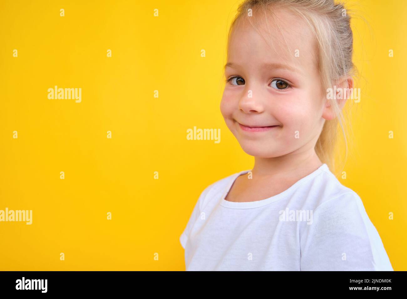 Vorschulmädchen suchen vorne schön natürlich lächelnd auf gelbem Hintergrund Stockfoto