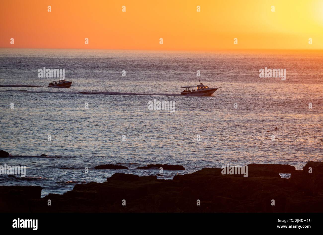 Vergnügungsboote bringen Menschen zum Sonnenuntergang in Godrevy, Cornwall, Großbritannien Stockfoto