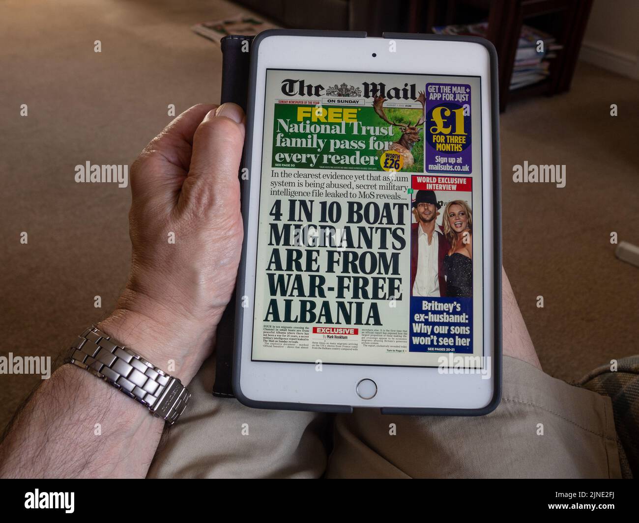 Mann beim Lesen der Mail am Sonntag, 7.. August 2022, auf einem iPad Mini; Schlagzeile über Bootsflüchtlinge aus Albanien Stockfoto