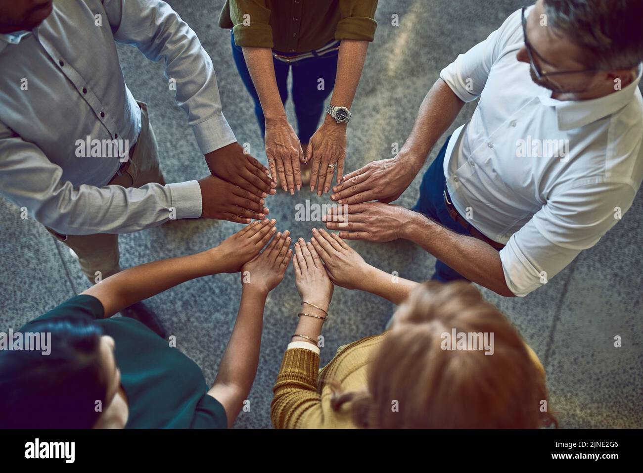 Geschäftsleute, die mit den Händen einen Kreis schließen, Teambuilding machen und Unterstützung zeigen, die von oben bei der Arbeit zusammen stehen. Kollegen, die sich mit Formen Stockfoto