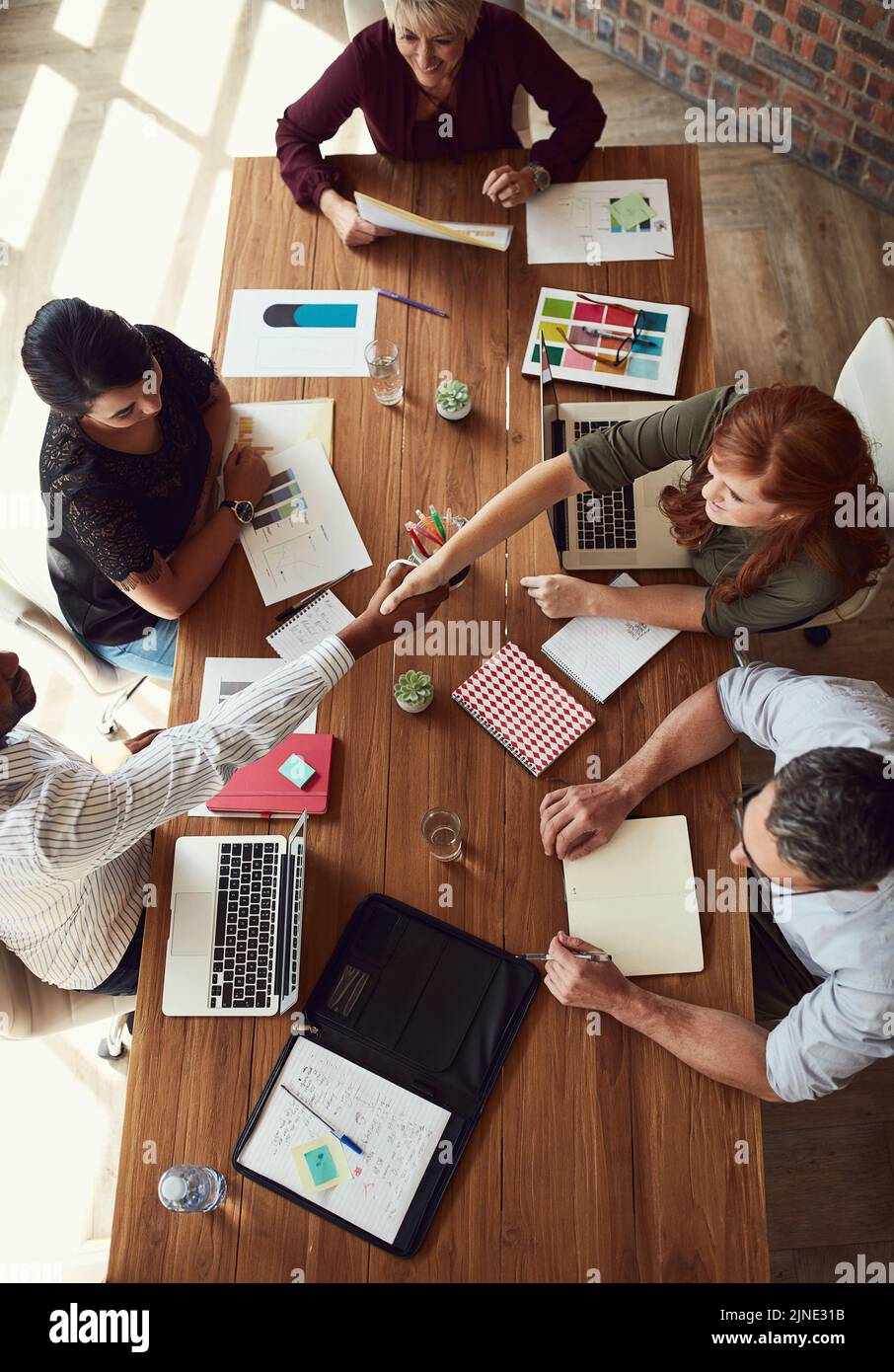 Händedruck, Zustimmung und Begrüßung des Teams kreativer Designer während eines gemeinsamen Meetings. Overhead-Ansicht einer vielfältigen Gruppe von Künstlern oder Stockfoto