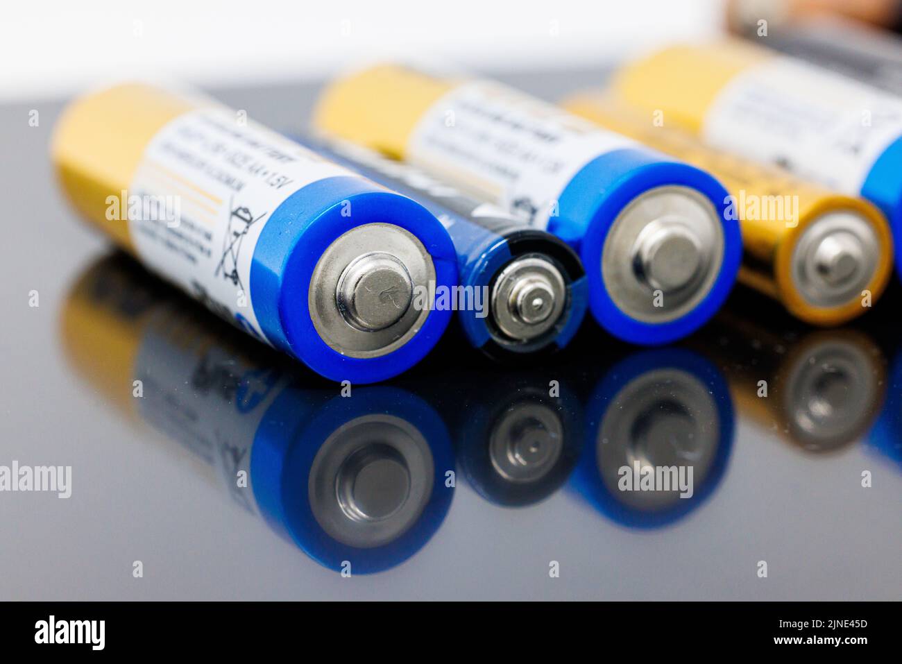 Eine Nahaufnahme einer Reihe von AAA- und AA-Batterien auf einer grauen reflektierenden Oberfläche Stockfoto