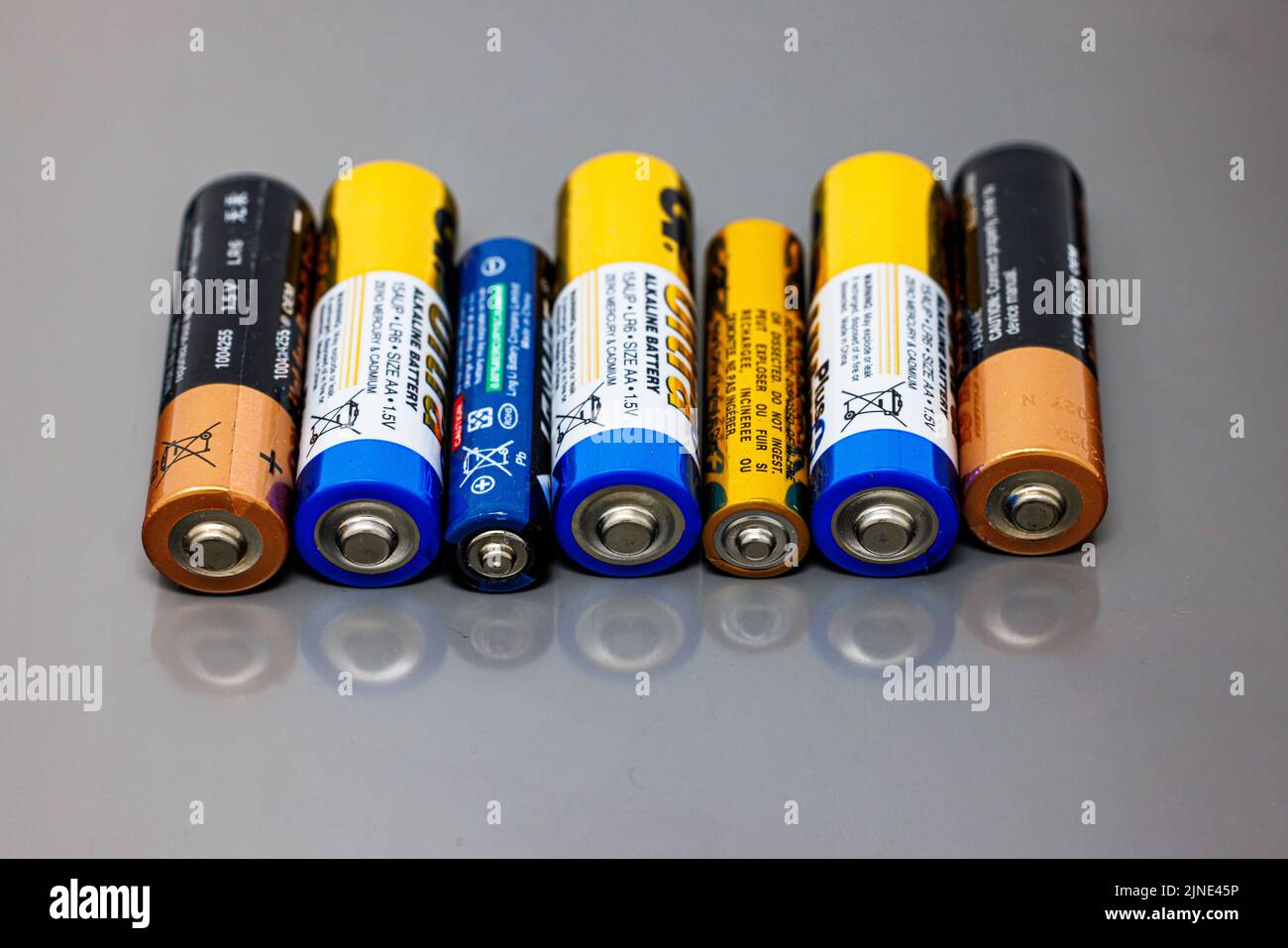 Eine Reihe von AAA- und AA-Batterien auf grauer reflektierender Oberfläche Stockfoto