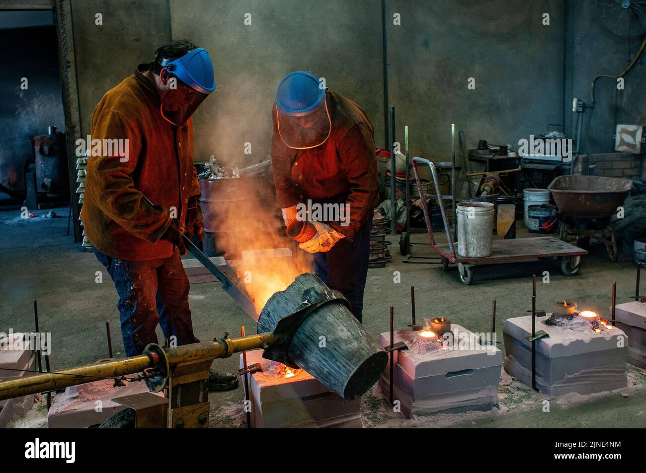 Gießereiarbeiter gießen in einer kleinen Familiengießerei in Perth, Westaustralien, geschmolzenes Metall in Formen Stockfoto