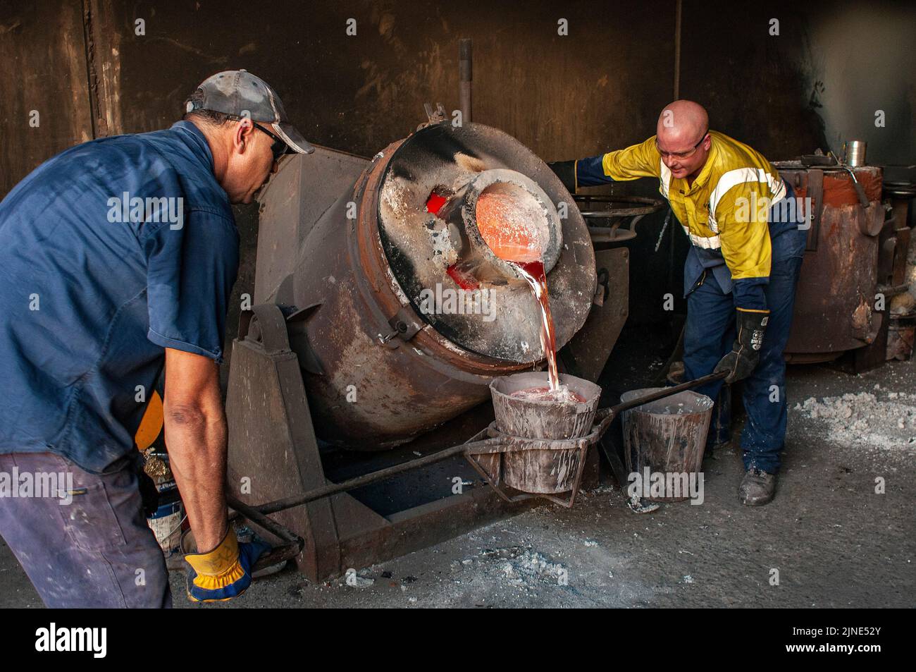 Gießereiarbeiter in einer kleinen Familiengießerei in Perth, Westaustralien, gießen geschmolzenes Aluminium aus einem Ofen Stockfoto