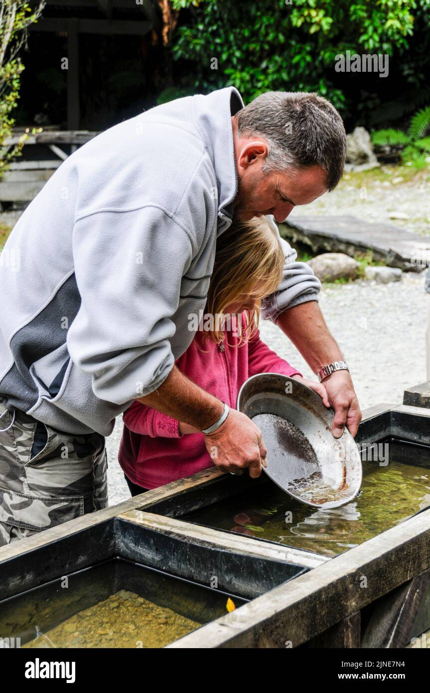 Ein Vater und eine Tochter versuchen ihr Geschick beim Goldwaschen im lebenden Museum einer alten Goldgräberstadt in Shantytown, südlich von Greymouth am We Stockfoto