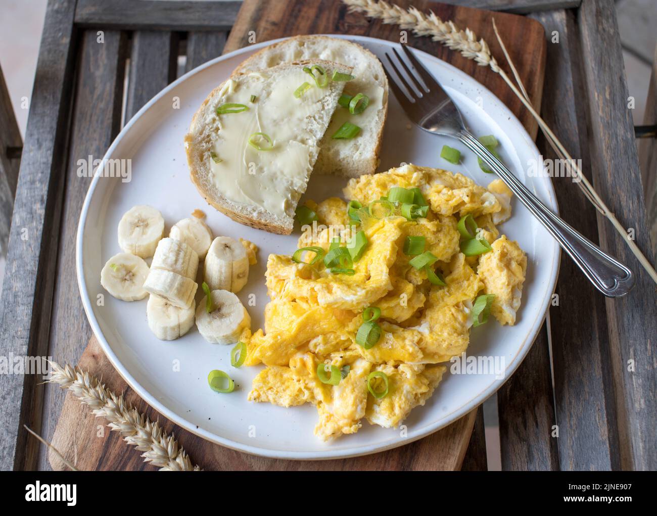 Frühstücksteller mit Rührei, Butterbrot und Bananen. Stockfoto