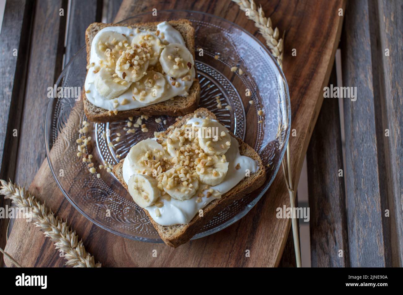 Toast zum Frühstück mit Quark, Bananen und gerösteten Nüssen. Stockfoto