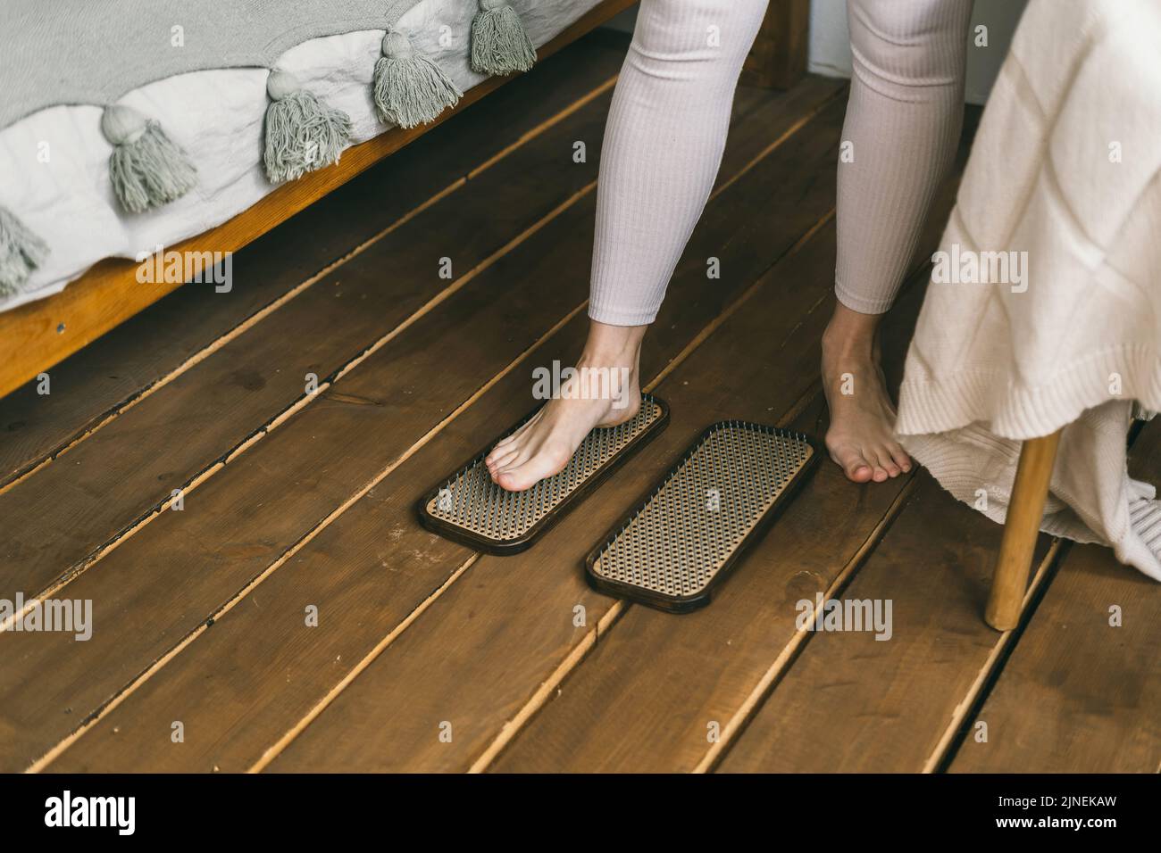 Nahaufnahme von menschlichen Beinen, die mit Nägeln auf einem Yoga-Brett aufstehen. Stockfoto