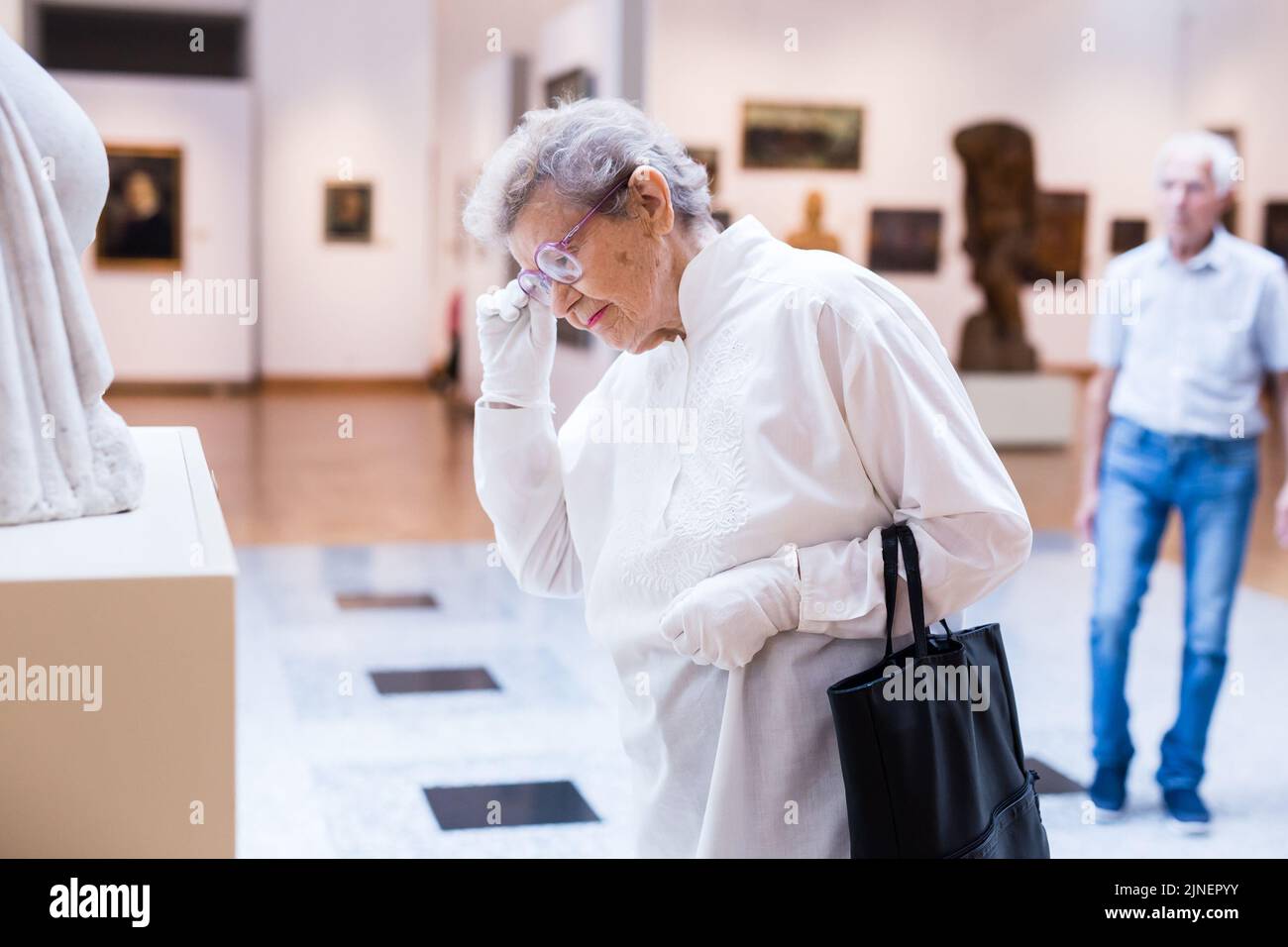 Reife Frau untersucht Skulptur in einer Ausstellung in der Halle eines Kunstmuseums Stockfoto