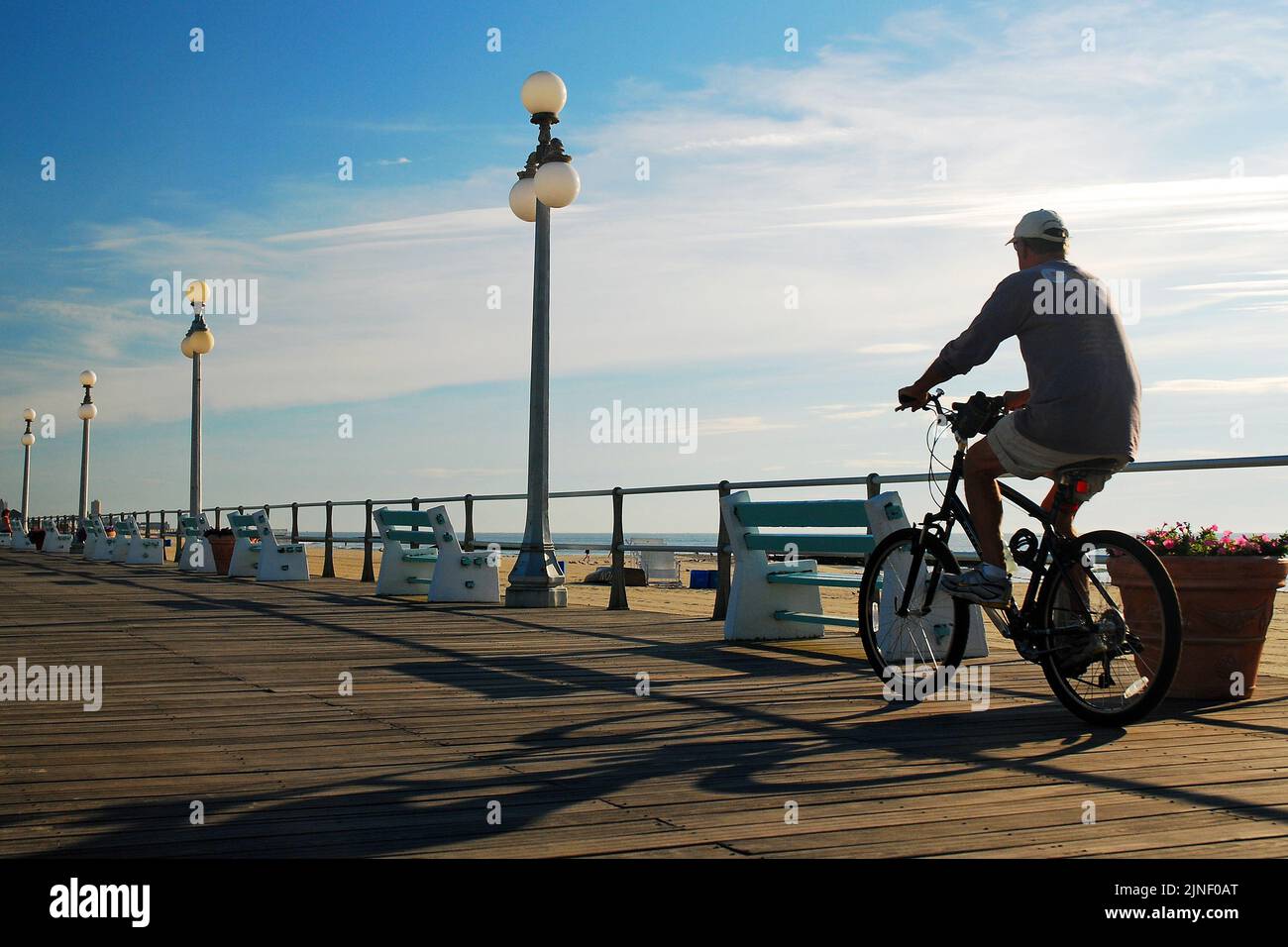 Ein männlicher Radfahrer fährt am frühen Morgen mit dem Fahrrad auf der Promenade in Avon by the Sea an der Küste von New Jersey, um sich zu bewegen und gesund zu leben Stockfoto