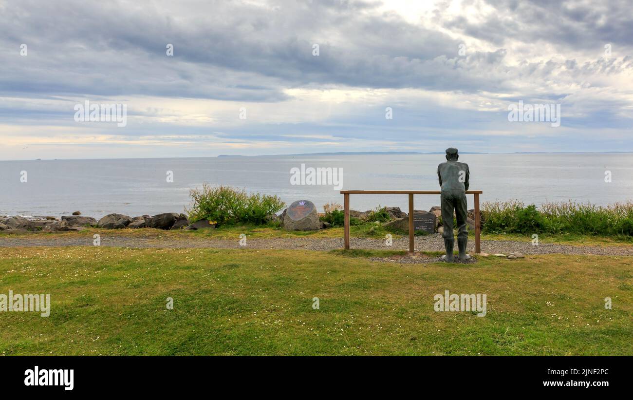 Port William , Schottland - 15. Juni 2022: Die Statue des Fisherman Memorial mit Blick auf die Luce Bay und einem wolkenverwitterten Himmel Stockfoto