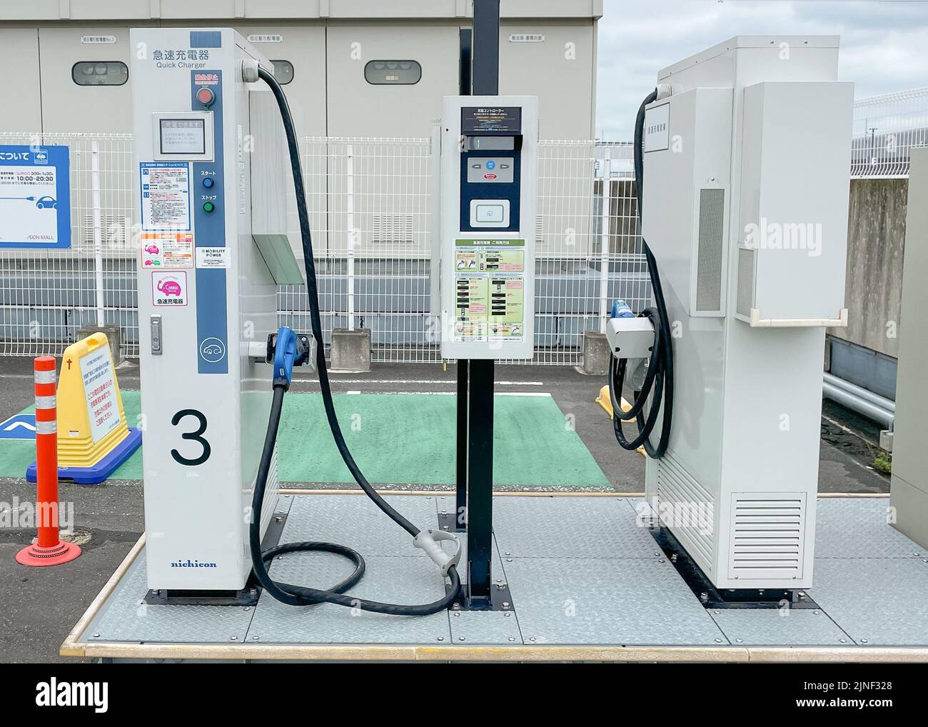 Zwei gegenüber liegende EV-Schnellladegeräte oder Schnellladegeräte auf einem Parkplatz auf dem Dach einer EON Mall mit einem einzigen Auto, das an einer der Stationen geladen wird Stockfoto