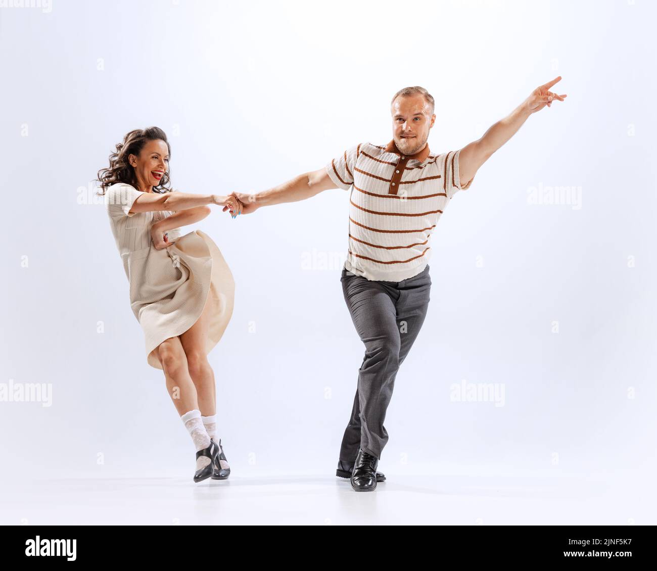 Dynamisches Porträt von emotionalen Mann und Frau tanzen Sporttänze isoliert auf weißem Hintergrund. 50s, 60s ,70s amerikanischer Mode-Stil. Stockfoto