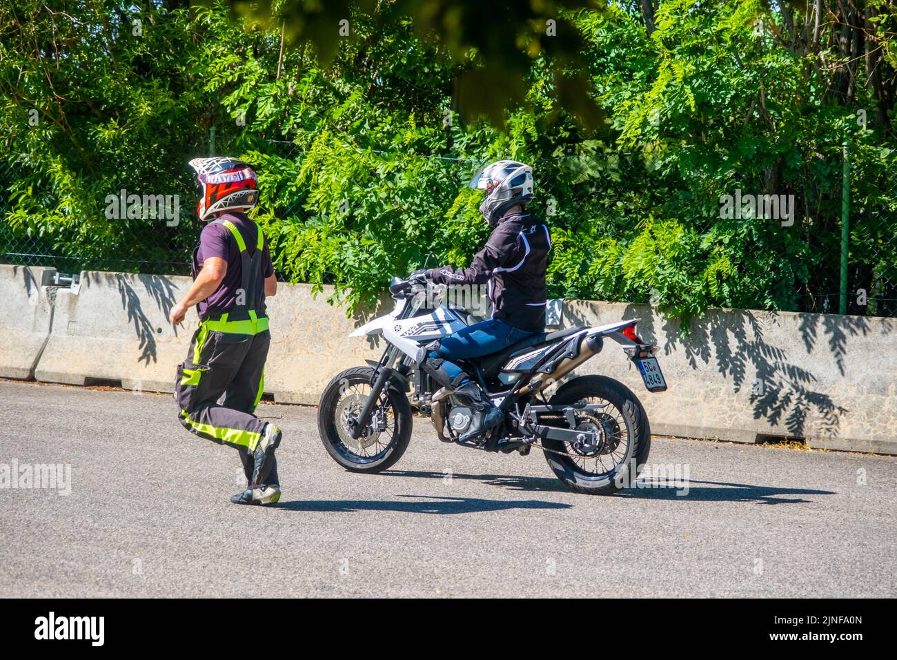 Prag, Tschechische Republik - 12. Juli 2022: Männlicher Instruktor kontrolliert den L-Fahrer, während sie im Geschicklichkeitstraining Motordrome Fahrrad fährt Stockfoto