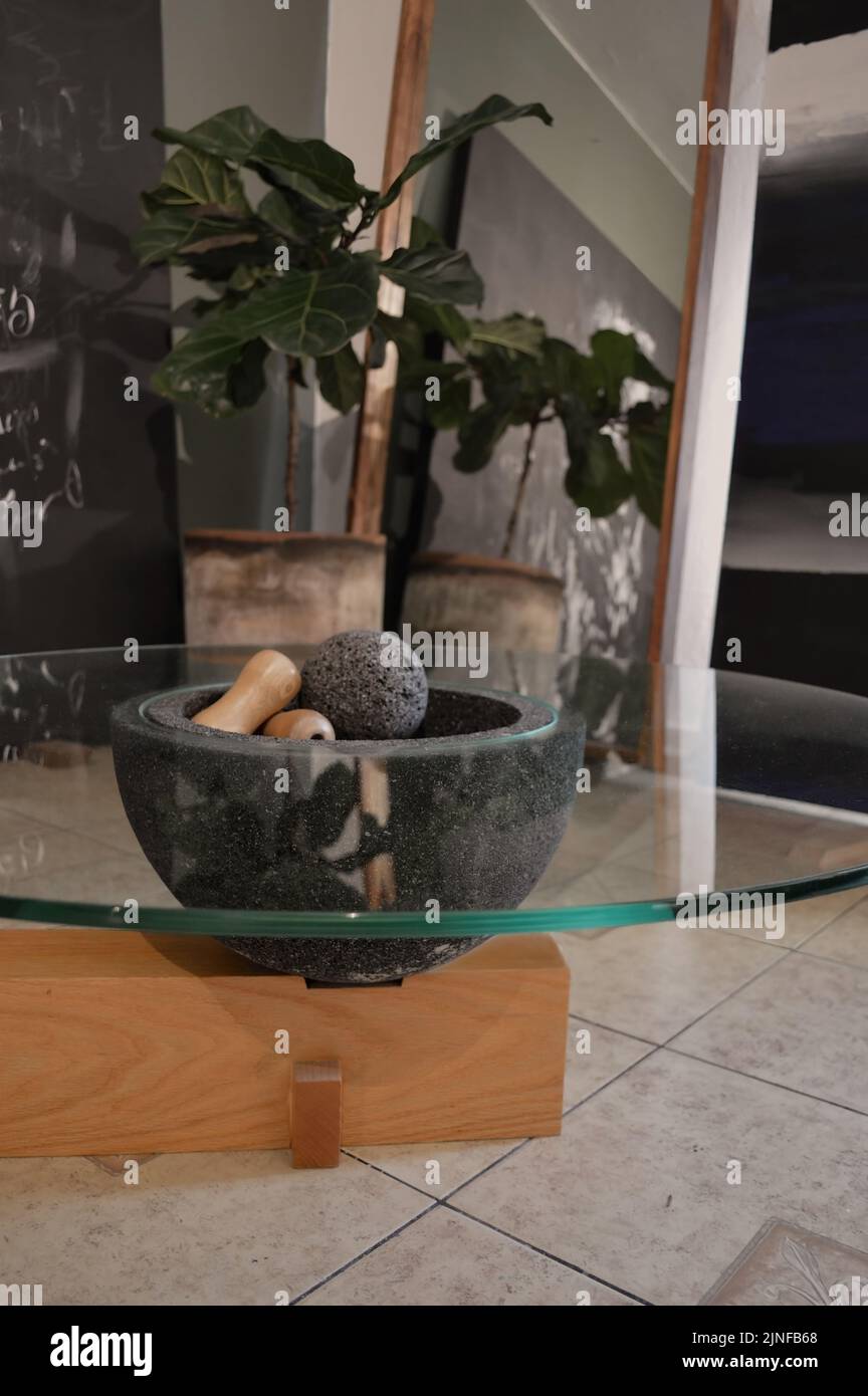 Eine vertikale Aufnahme aus schwarzen Granitkugeln und Holzstäben in einer schwarzen Schale, die in einem Tischglas platziert ist, ideal für die Inneneinrichtung Stockfoto