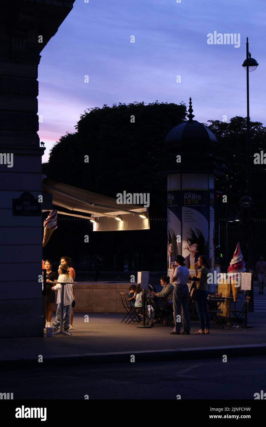 In der Abenddämmerung in Paris bestellen und genießen die Menschen vor einer Eisdiele Eis. Entspannte Sommerabende. Stockfoto