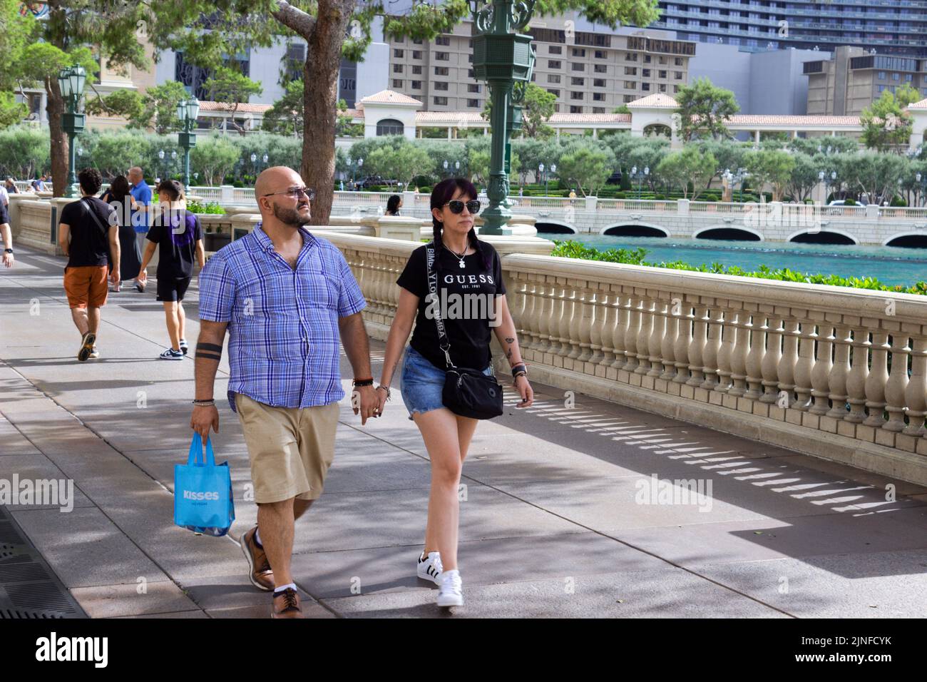 Ein junges Paar durchstreift den Strip in Las Vegas und hält sich die Hände. Stockfoto