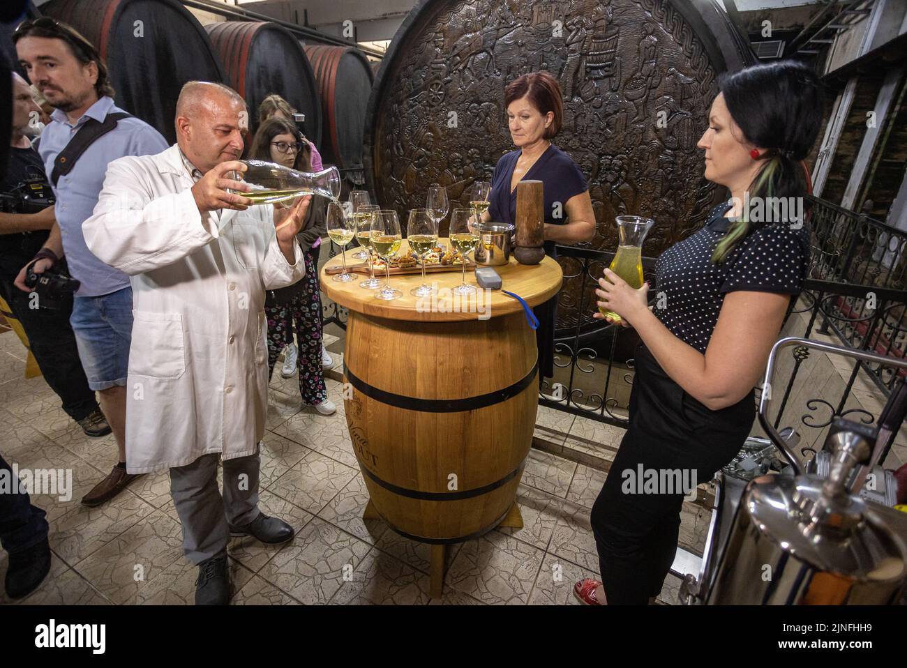 Der Chefönologe Damir Risek gießt am 11. August 2022 Wein aus dem Big Barrel der Weinberge von Erdut in Erdut, Kroatien. Das Big Barrel of Erdut Vineyards ist das größte in der Welt verwendete Weinfass. Sein Fassungsvermögen beträgt 75.000 Liter, das sind 100.000 Flaschen Wein. Das Fass ist mit zweieinhalb Tonnen Fesseln verkettet, mit kroatischen Korbreliefs verziert, sowie mit dem Letzten Abendmahl, wo Jesus einen Kelch Wein hält, und wurde von den naiven Bildhauern Tijardovic und Fodor dekoriert. Sie ist aus 150 Jahre alter slawonischer Eiche gefertigt und wurde 1989 von DIK Djurdjenovac hergestellt. Das Fass wurde mit gebaut Stockfoto