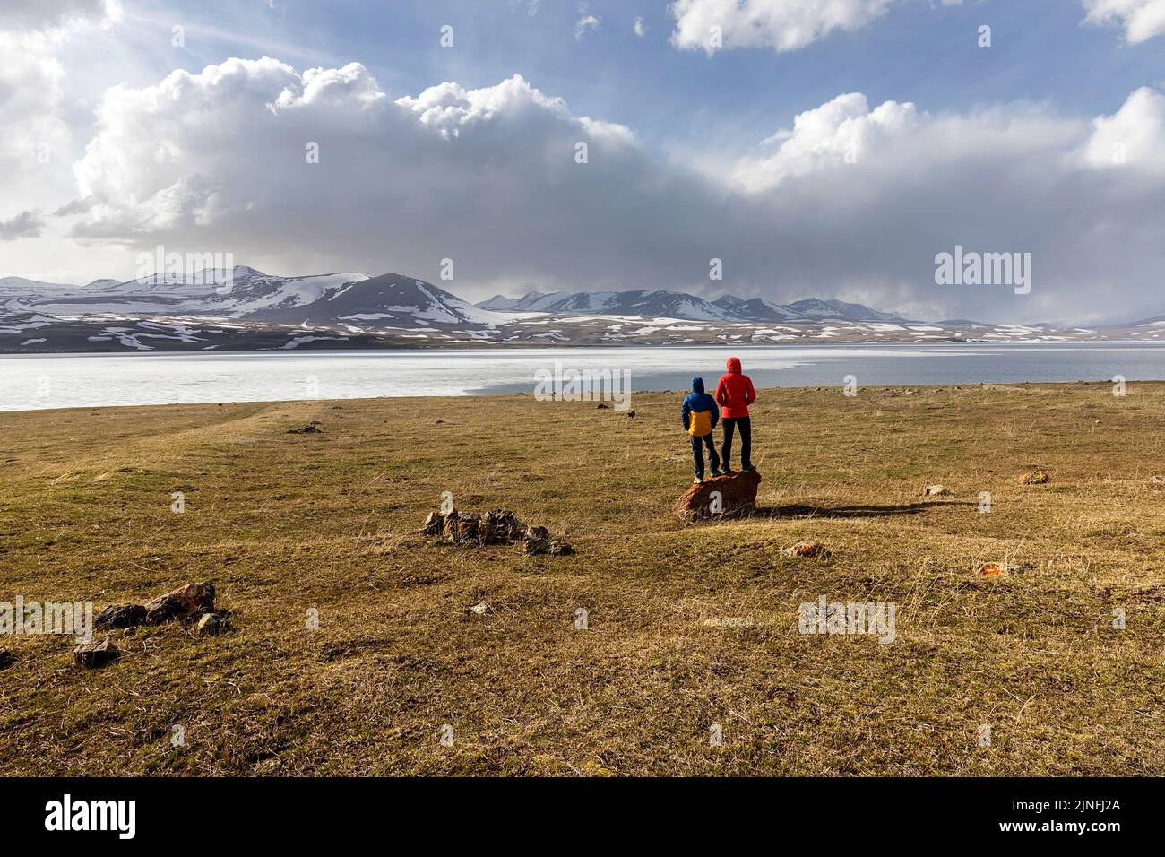 Touristen auf einem Roadtrip durch Georgien, mit Blick auf den gefrorenen See Paravani und die schneebedeckten Berge im Hintergrund, das VulkankPlateau Javakheti Stockfoto