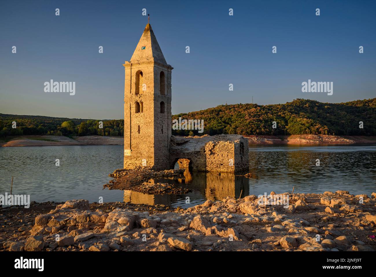 Sonnenaufgang am Glockenturm von Sant Romà de Sau und dem Stausee Sau während der Sommertrockenheit von 2022 (Osona, Barcelona, Katalonien, Spanien) Stockfoto