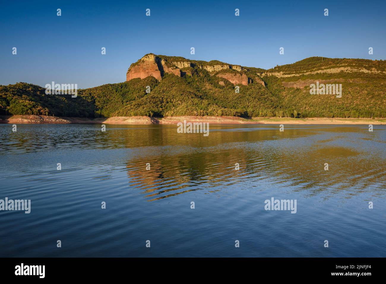 Sonnenaufgang am Glockenturm von Sant Romà de Sau und dem Stausee Sau während der Sommertrockenheit von 2022 (Osona, Barcelona, Katalonien, Spanien) Stockfoto