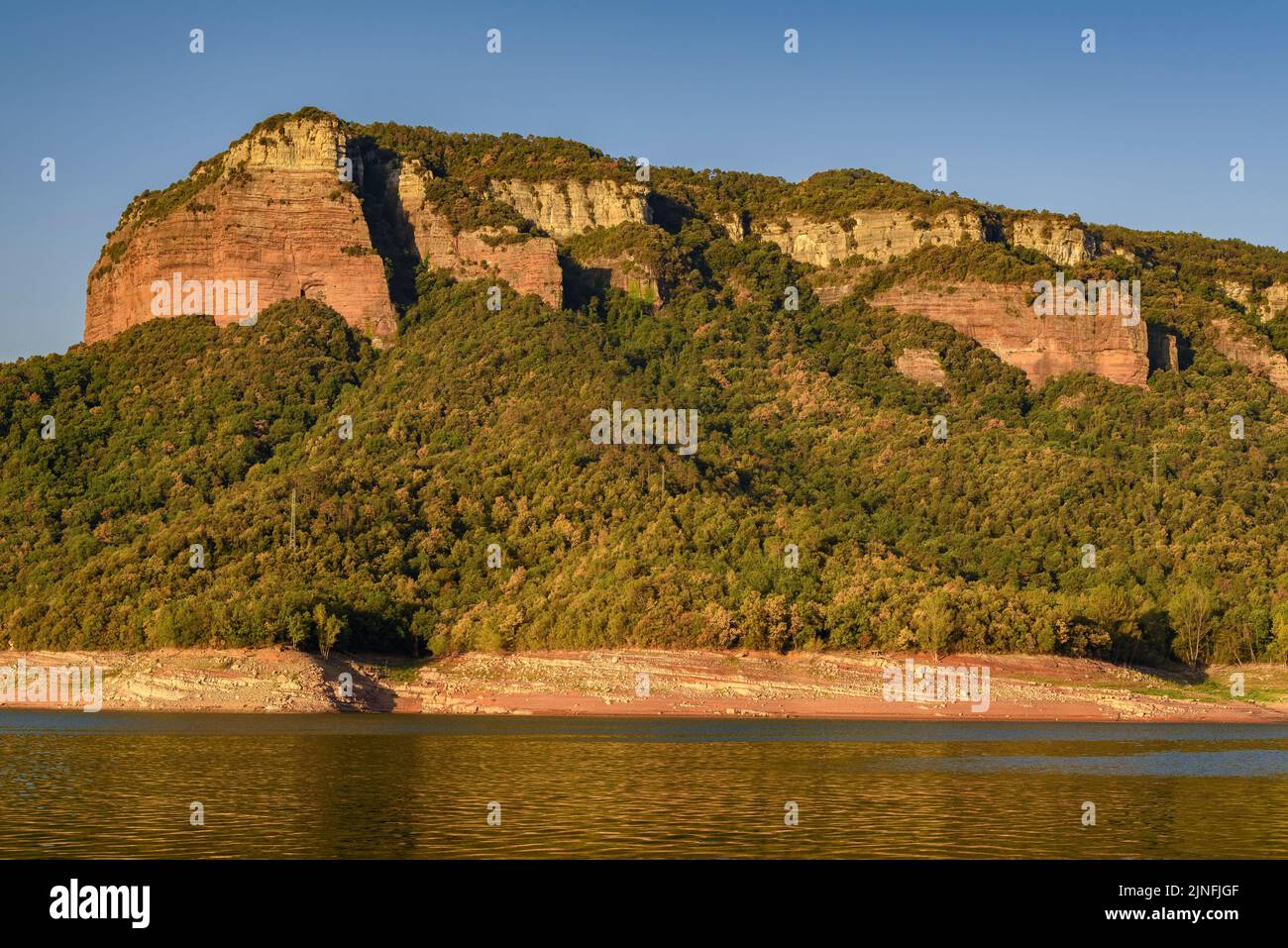 Sonnenaufgang am Glockenturm von Sant Romà de Sau und dem Stausee Sau während der Sommertrockenheit von 2022 (Osona, Barcelona, Katalonien, Spanien) Stockfoto