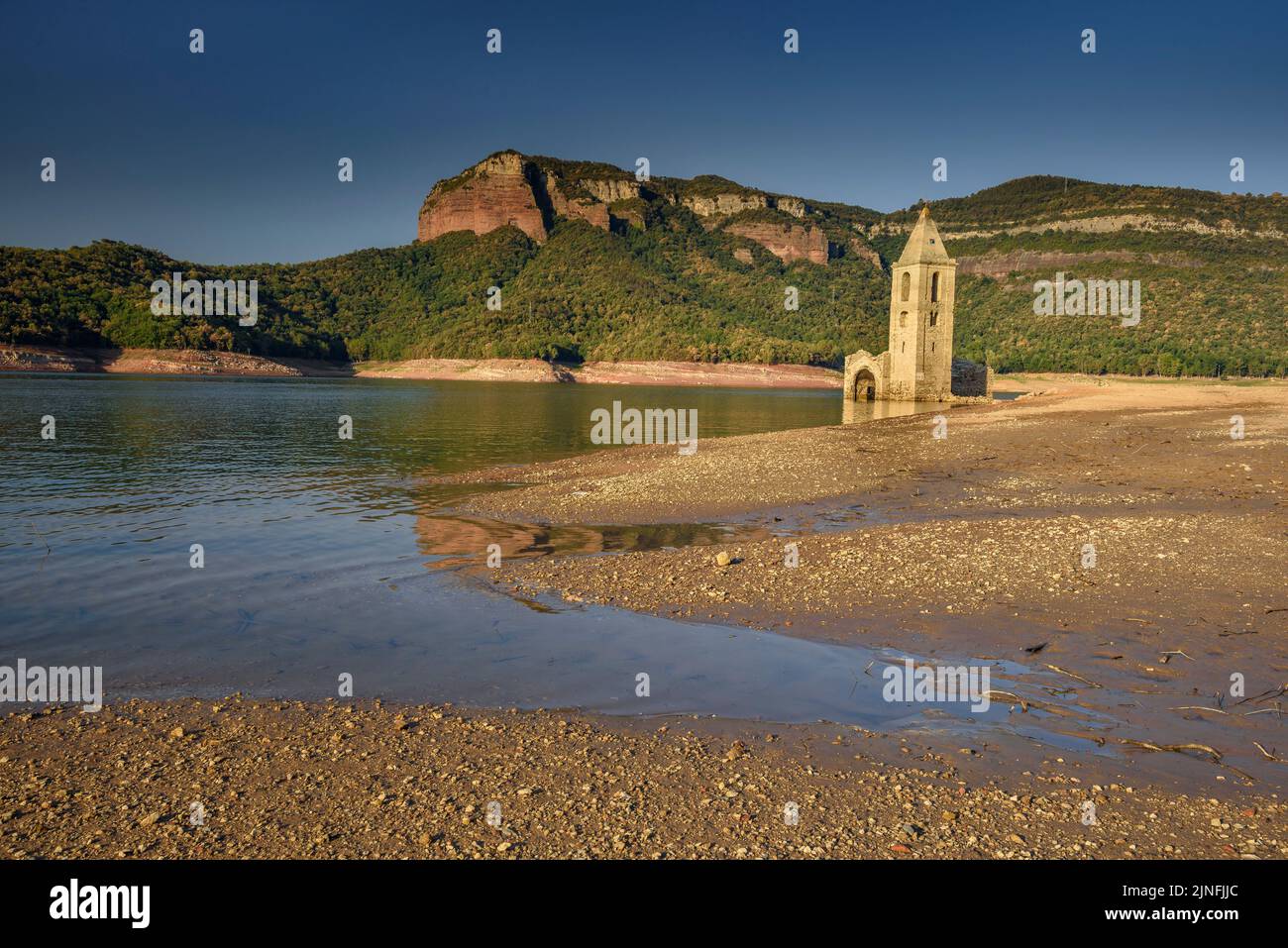 Sonnenaufgang am Glockenturm von Sant Romà de Sau und dem Stausee Sau während der Sommertrockenheit von 2022 (Osona, Barcelona, Katalonien, Spanien) Stockfoto