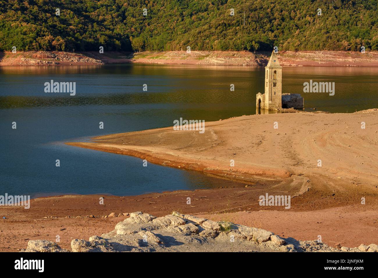 Sonnenaufgang am Glockenturm von Sant Romà de Sau und dem Stausee Sau während der Sommertrockenheit von 2022 (Osona, Barcelona, Katalonien, Spanien) Stockfoto