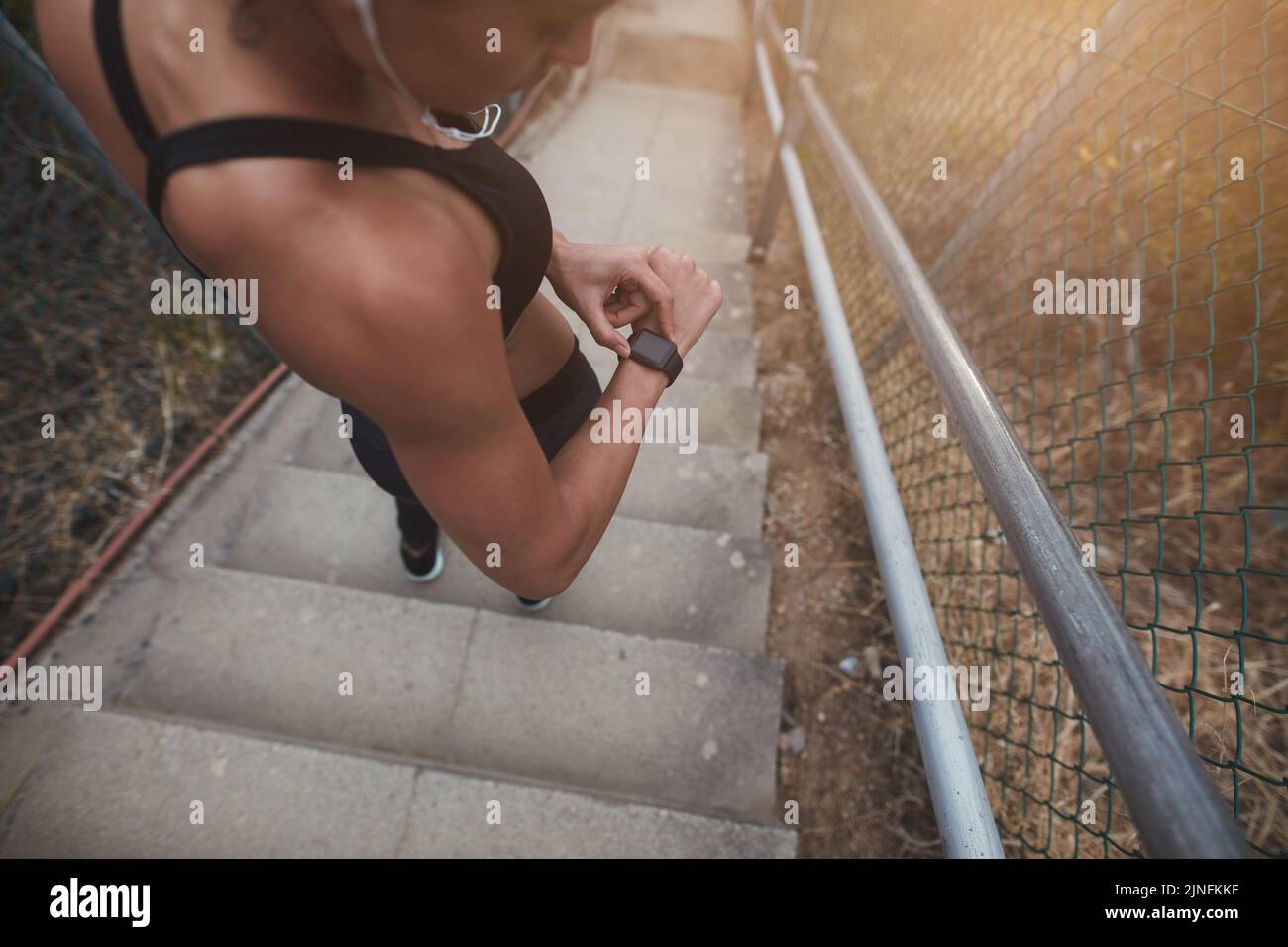 Eine athletische junge Frau überprüft ihr Smartphone, um ihren Fortschritt im Freien zu überwachen. Sportliche junge Frau, die morgens ein körperliches Training absolviert. Stockfoto