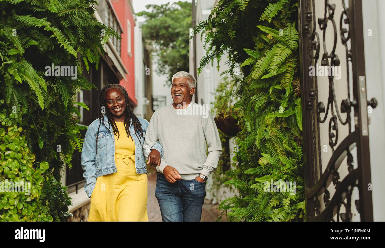 Glückliches Senioren-Paar, das fröhlich lacht, während es draußen zusammen geht. Fröhliches Seniorenpaar, das nach dem Ruhestand einige gute Zeit miteinander verbringt. Stockfoto