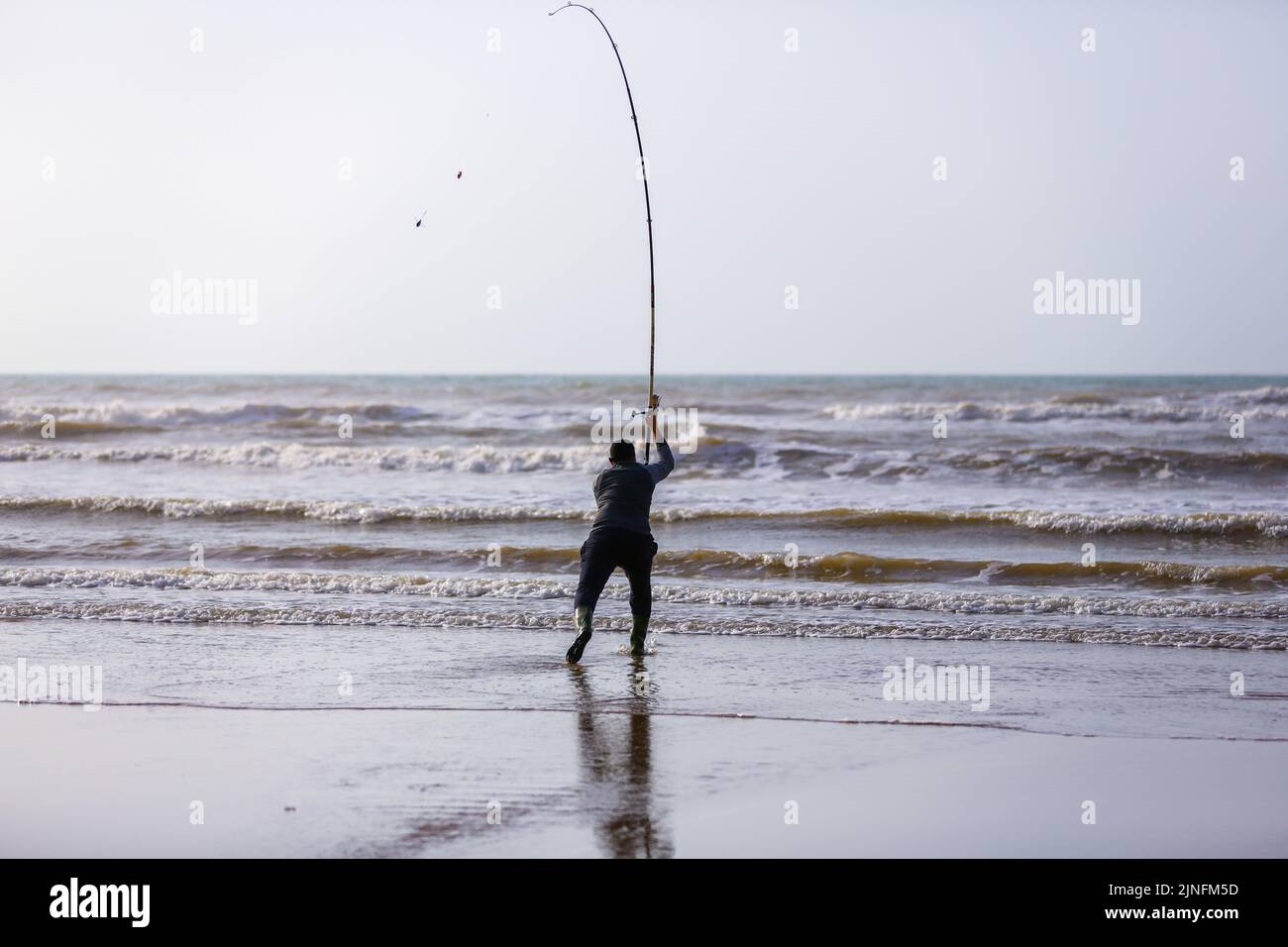 Ein Fischer warf seinen Haken mit seiner Angelrute Stockfoto