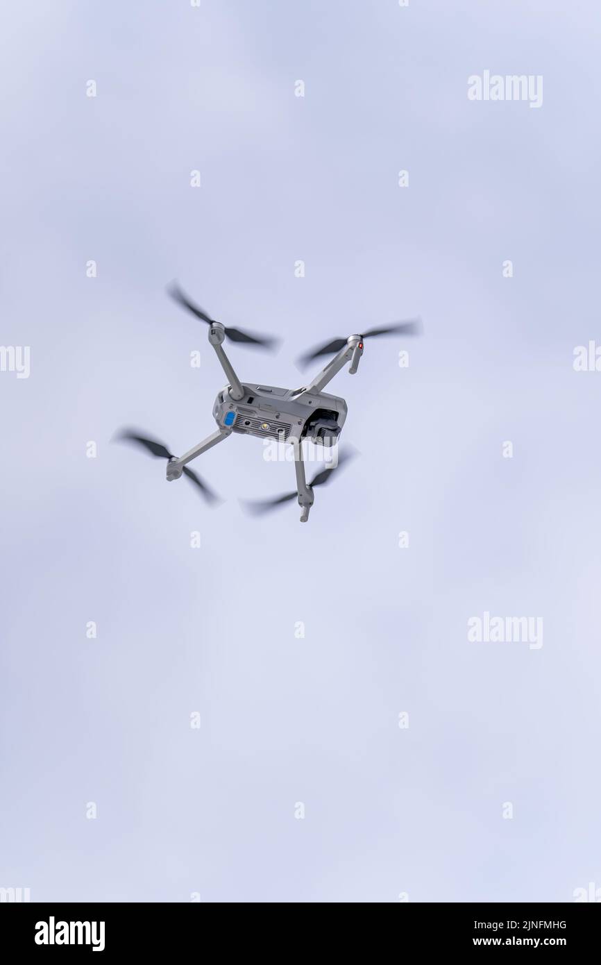 Eine vertikale Aufnahme einer fliegenden DJI-Drohne durch die Luft unter bewölktem Himmel Stockfoto