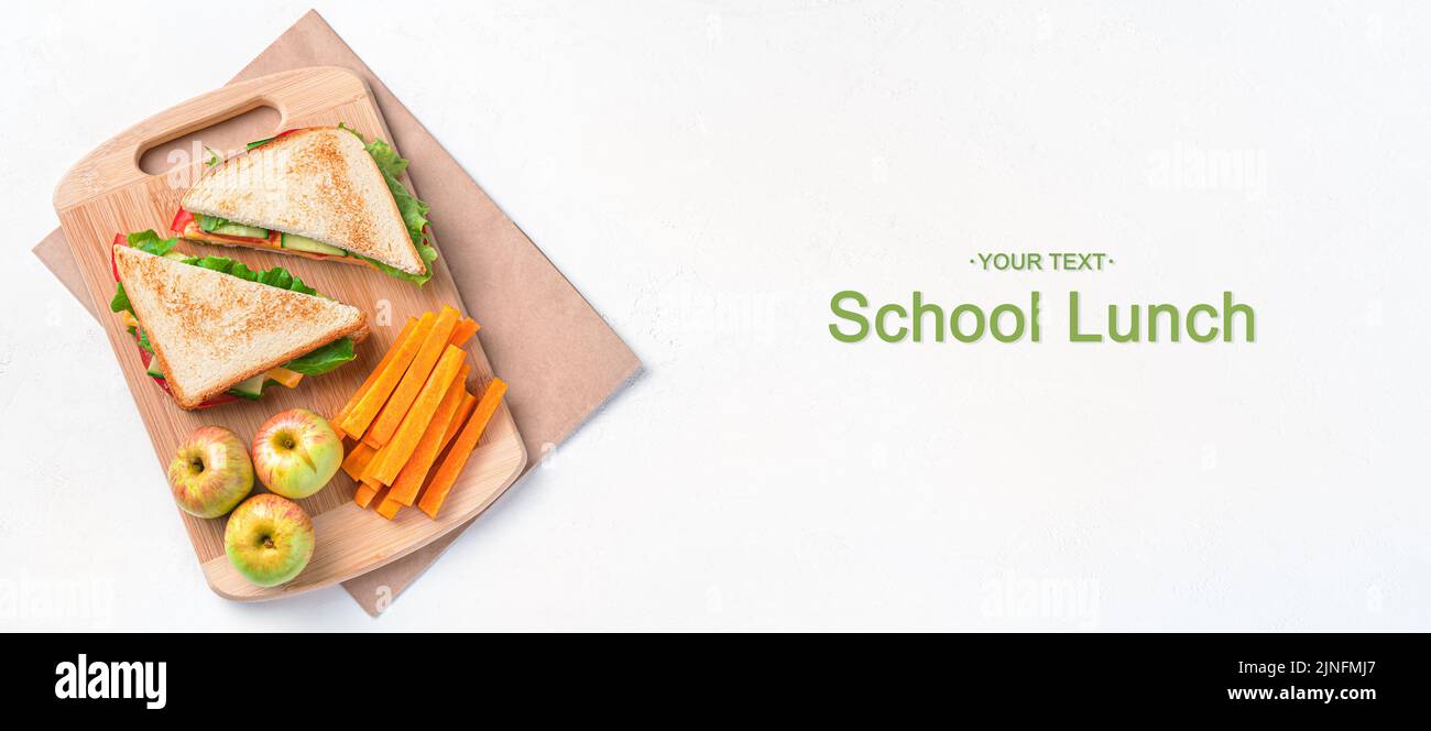 Sandwich, Äpfel und Karotten auf grauem Hintergrund. Schulessen. Stockfoto