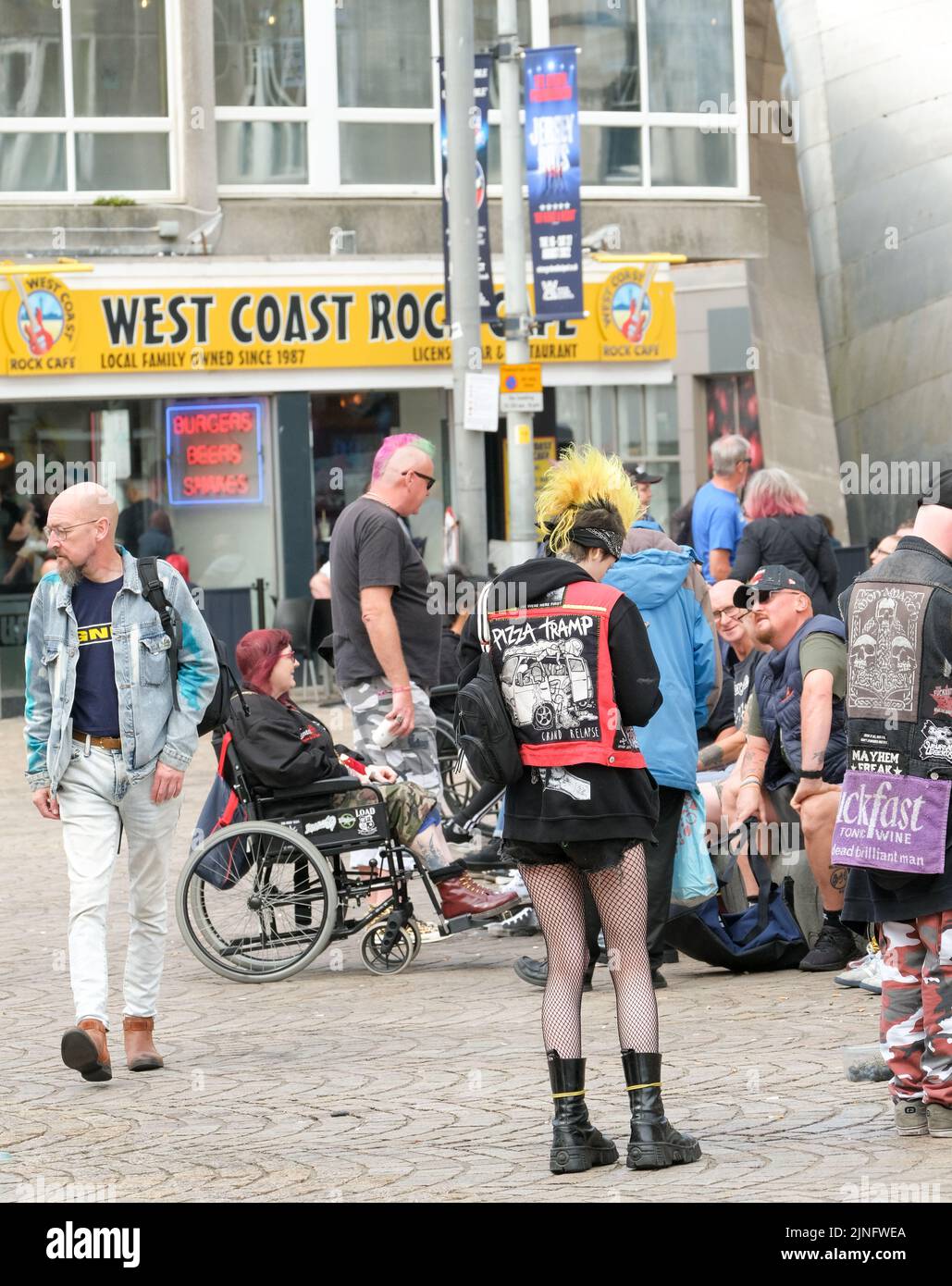 Blackpool, Lancashire, UK August 6 2022 Ein junges Mädchen mit gelbem mohican-Haarschnitt und Fischnetz-Strumpfhosen mischt sich mit einer Gruppe von anderen Punks Stockfoto