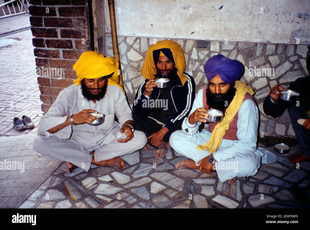 Amritsar India Männer sitzen mit gekreuzten Beinen und essen Langar im Goldenen Tempel Stockfoto