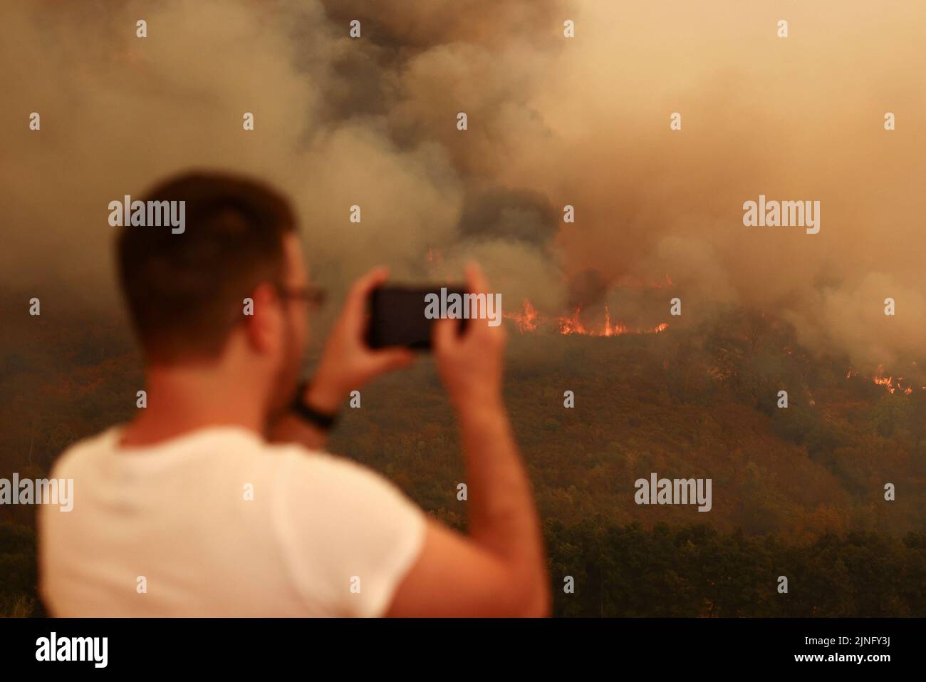Eine Person fotografiert ein Waldfeuer in Carrapichana, Celorico da Beira, Portugal, 11. August 2022. REUTERS/Pedro Nunes Stockfoto