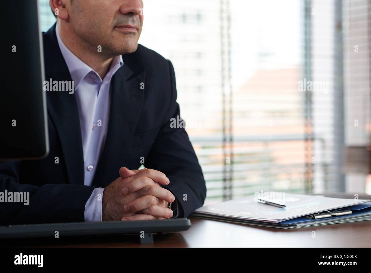 Beschnittenes Bild eines Geschäftsleitisten, der an seinem Tisch sitzt Stockfoto