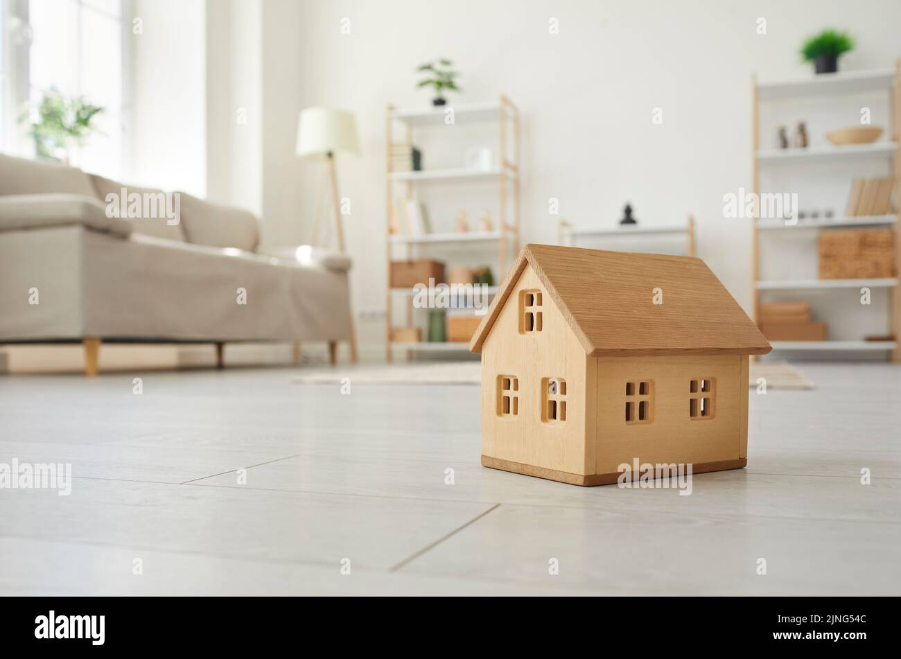 Nahaufnahme des kleinen Modells von Holz einstöckigen Haus auf dem Boden im Wohnzimmer der hellen Wohnung. Stockfoto