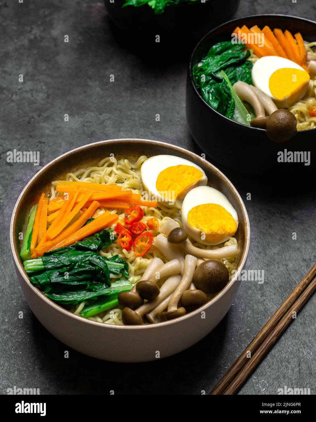 Asiatische Nudeln Suppe mit Pilzen, Eiern, dan sortiertes Gemüse auf dunklem Hintergrund. Stockfoto