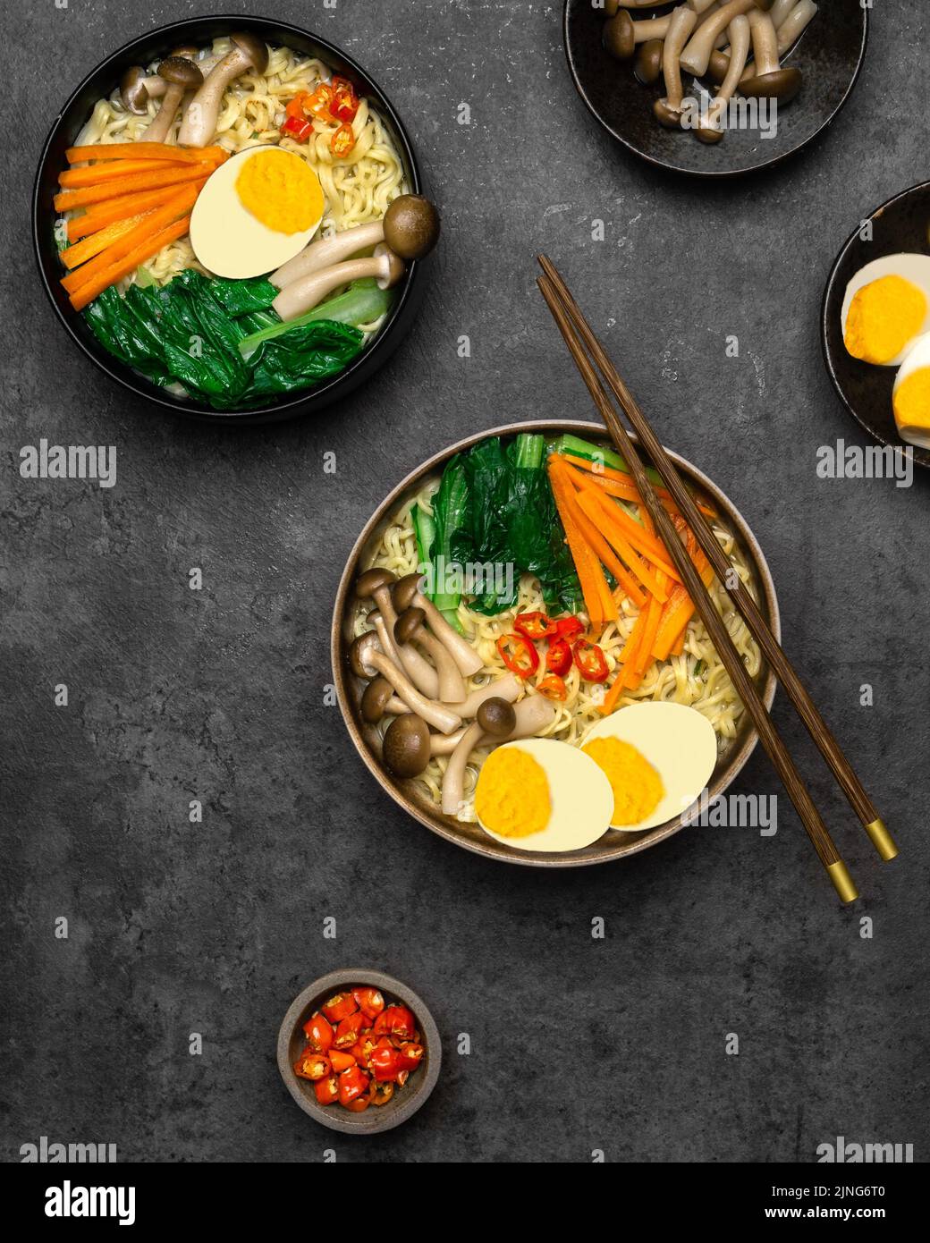 Asiatische Nudeln Suppe mit Pilzen, Eiern, dan sortiertes Gemüse auf dunklem Hintergrund. Stockfoto
