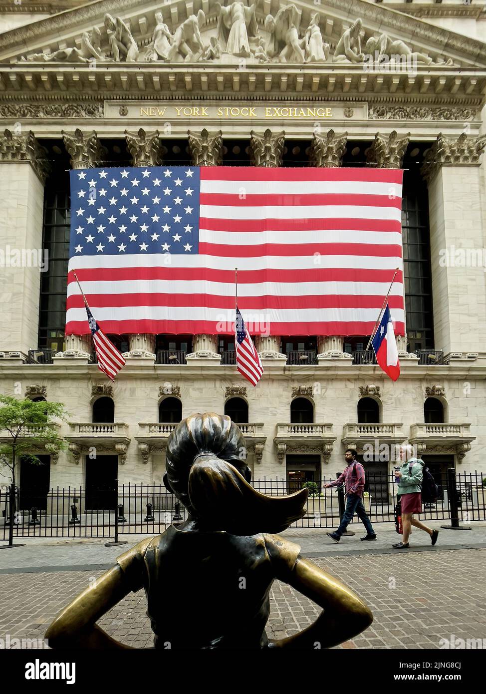 Fearless Girl Statue von hinten mit der New Yorker Börse im Hintergrund. Das Hotel liegt im Finanzdistrikt in New York City, USA. Stockfoto