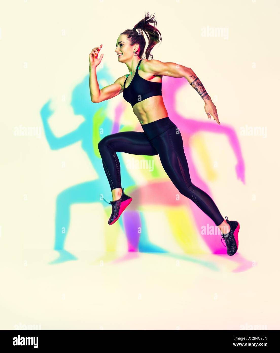 Sportliche Läuferin in Silhouette. Foto von muskulösen Frau in schwarzer Sportkleidung auf weißem Hintergrund mit Effekt von rgb-Farben Schatten. Dynamische Bewegung Stockfoto