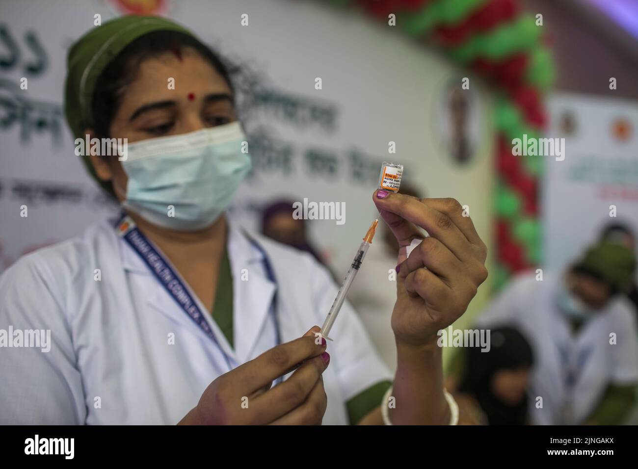 Ein Gesundheitsmitarbeiter bereitet sich darauf vor, einem Studenten des Bangabandhu International Conference Center eine Dosis des Impfstoffs Pfizer-BioNTech Covid-19 zu verabreichen. Bangladesch hat damit begonnen, Studenten ab 5-11 Jahren Coronavirus-Impfstoffe zu verabreichen. Stockfoto