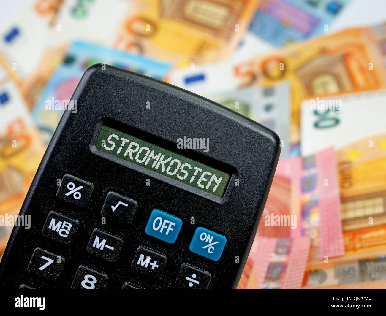Rechner mit dem Wort 'Stromkosten', Übersetzung 'Stromkosten' auf dem Display vor den Banknoten Stockfoto