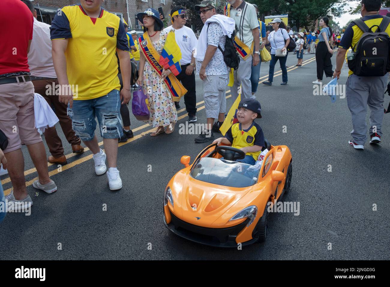 Ein unglücklicher junger ecuadorianischer Junge fährt kurz vor der ecuadorianischen Parade NYC 2022 in Jackson Heights, Queens, NYC, mit seinem Elektroauto in der 69. Street. Stockfoto